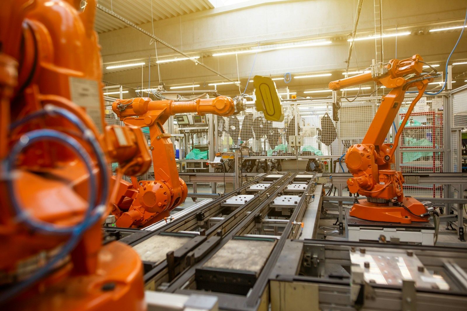 Fertigungshalle der Automobilindustrie mit orangefarbenen Industrierobotern – Lackieranlagen und Reinraumbereiche brauchen einen stabilen Überdruck gegen Staub