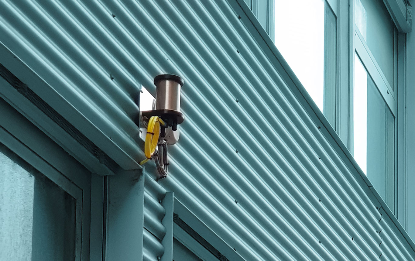 HaNu 2009 auf Edelstahlkonsole an der Wellblechfassade eines Produktionsgebäudes, gelbes Kabel